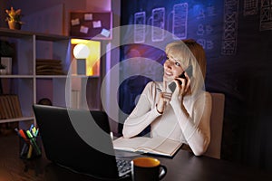 Woman having phone conversation while working late