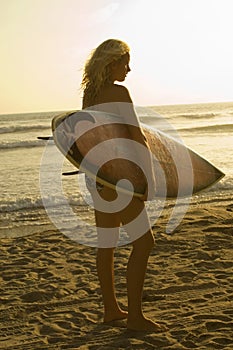 Female surfer carrying surfboard on beach