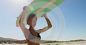 Female surfer carrying surfboard on her head 4k