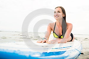 Female surfer paddling on surfboard to the open sea