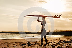 female surfer posing with surfboard on head