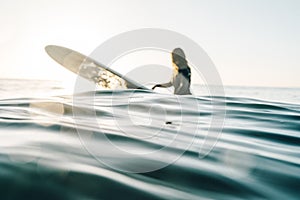 Female surfer surfing with a longboard at the Cordoama Beach on a sunny day in Algarve, Portugal