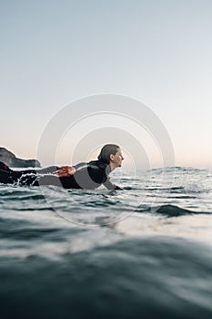 Female surfer surfing with a longboard at the Cordoama Beach on a sunny day in Algarve, Portugal