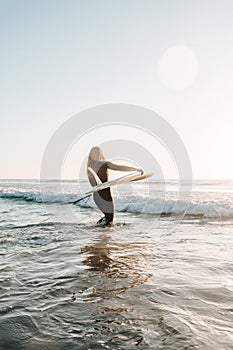 Female surfer surfing on a longboard at the Cordoama beach on a sunny day in Algarve, Portugal