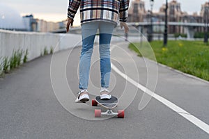 Female surfing city street on skateboard outdoors. Mixed race african casual woman riding longboard