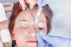 Surgeon applies a bandage to the female patient`s eyelids after