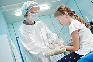 female surgeon doctor bandaging child's hand in clinic