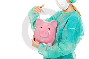 Female surgeon doctor holding piggy bank