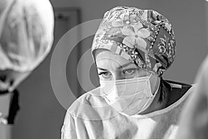 Female surgeon doctor wearing protective mask and hat during the operation. Healthcare, medical education, emergency