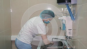 A female surgeon is getting ready for surgery. She washes her hands in a special place.