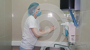 A female surgeon is getting ready for surgery. He washes his hands. Uses a special gel for disinfection.