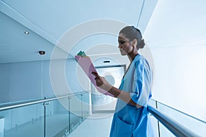 Female surgeon looking medical reports in the corridor of hospital