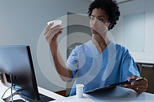 Female surgeon looking at medicine on desk in hospital