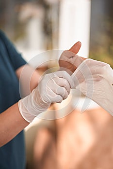 Female surgeon or nurse wearing a sterile suit putting on sterile rubber gloves to perform a surgery