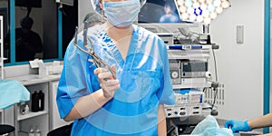 A female surgeon in the operating room holds an anus dilator.