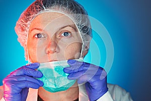 Female surgeon puts on protective surgical mask before operation