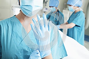 Female surgeon putting on gloves in the operating room, midsection