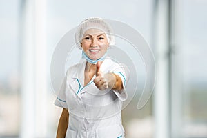 Female surgeon showing thumb up.