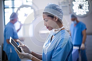 Female surgeon using digital tablet in operation room