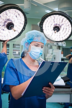 Female surgeon writing on clipboard in operation room