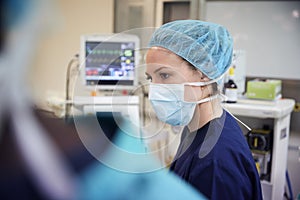 Female Surgical Team Member Working On Patient In Hospital Operating Theatre