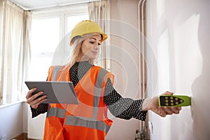 Female Surveyor With Digital Tablet Measuring Room With Laser Measure photo