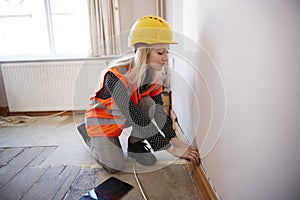 Female Surveyor In Hard Hat And High Visibility Jacket With Digital Tablet Carrying Out House Inspection