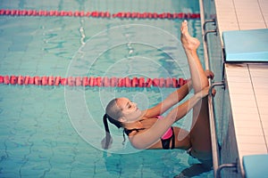 A female swimmer in indoor sport swimming pool. girl in pink sweimsuit training