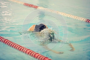 A female swimmer in indoor sport swimming pool trying to dive.