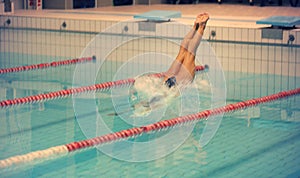 A female swimmer, that jumping and diving into indoor sport swimming pool. Sporty woman.