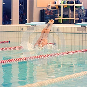 A female swimmer, that jumping and diving into indoor sport swimming pool. Sporty woman.