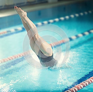 Female swimmer, that jumping into indoor swimming pool.