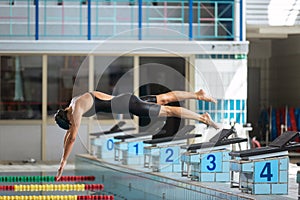 Female swimmer jumping into a pool from the starting block