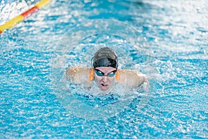Female swimmer moving through the water performs a butterfly stroke