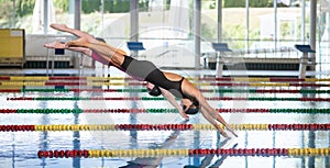 Female swimmer preparing and jumping off the starting block