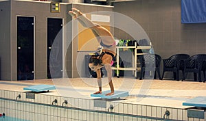 A female swimmer, that ready to jump into indoor sport swimming pool. standing on arms with legs up
