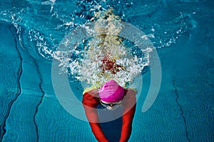 Female swimmer in a red suit and glasses sunk into the water to make a U-turn.