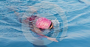Female swimming laps in a pool wearing a pink bathing cap
