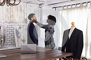 Female tailor fitting businessman for suit in tailor shop