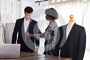 Female tailor fitting businessman for suit in tailor shop