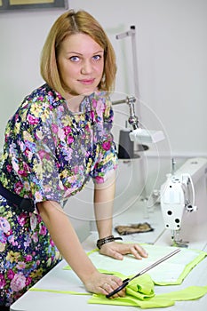 Female tailor stands near table with tailoring photo