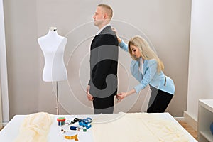 Female Tailor Taking Measurement Of Man's Suit