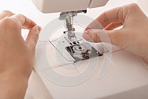 Female tailor threading sewing machine, closeup
