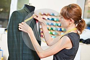 Female tailor works with male suit