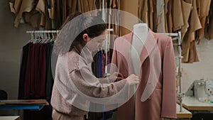 female tailoring fashion designer measuring suit jackets on mannequin dummy in workshop studio atelier.