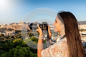 Female takes photographs of the cityscape and Acropolis of Athens, Greece