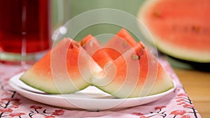 Female taking a bite of a slice of juicy watermelon from the ceramic plate