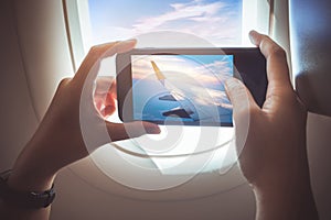 Female taking a photo with smartphone on plane.Holiday travel