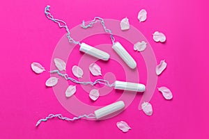 Female tampons with with cherry petals on a pink background. Hygienic white tampon for women. Cotton swab