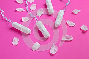 Female tampons with with cherry petals on a pink background. Hygienic white tampon for women. Cotton swab